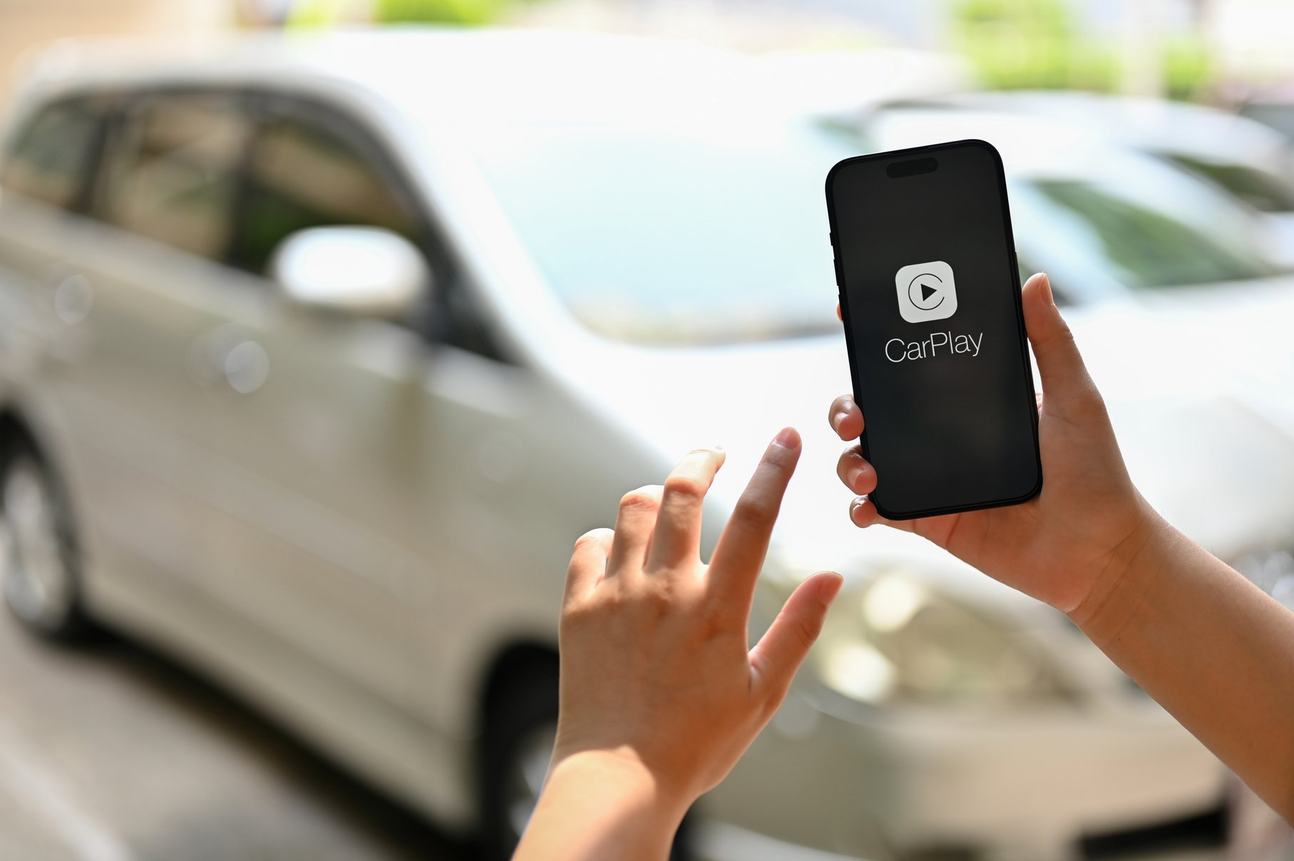 A female hand holding an iPhone with the CarPlay logo on screen